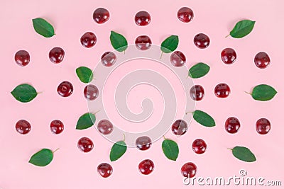 Ripe cherries and green leaves arranged in a circle on a pink background. Concept of berries season and proper nutrition Stock Photo