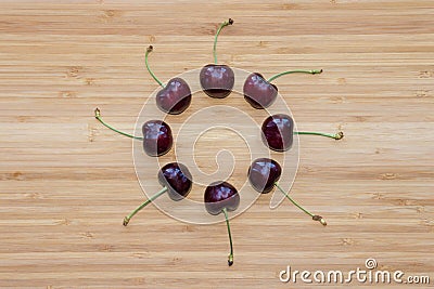 Ripe dark red cherries in circle on wooden board Stock Photo