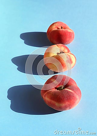 Ripe flat peaches on blue background. Summer fresh fuzzy fruit, natural farm harvest. Doughnut peach or Saturn peach. Diet vegan Stock Photo