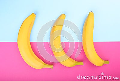 Ripe, fresh and sweet yellow bananas on a bright pink and light blue background. Tropical bananas. Banana, close-up. Stock Photo