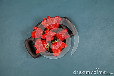 Ripe funny strawberry berries on wooden plate, top view. Blue background, copy space. Ugly fruits and vegetables can be eaten. Stock Photo