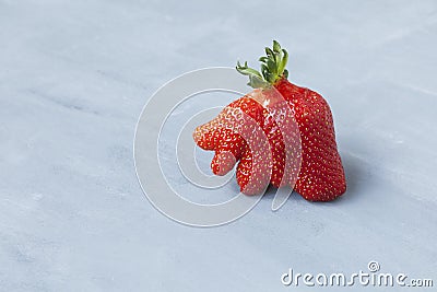 Ripe funny strawberry berry. Trendy food. Concept - Eating ugly fruits and vegetables. Space for text Stock Photo