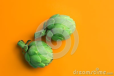 Ripe green artichokes on bright solid orange background. Creative food poster. Minimalist style. Mediterranean Spanish cuisine Stock Photo