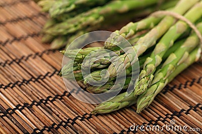 Ripe green mini asparagus on wooden mat Stock Photo