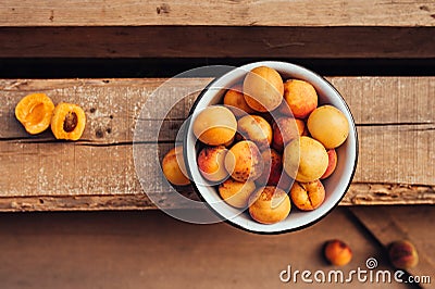 Ripe juicy homemade apricots with cracks and flaws in the plate and scattered on wooden boards, top view Stock Photo