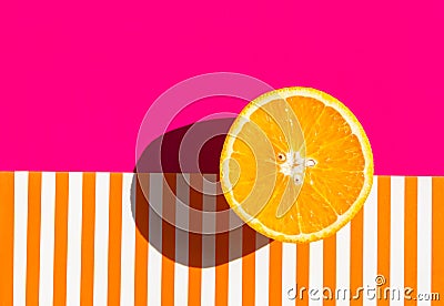 Ripe juicy raw orange cut in half on duotone pink striped background. Citrus fruits healthy diet vitamins concept. Trendy poster Stock Photo