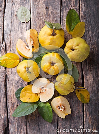 Ripe large quince fruit and slice with green foliage in late autumn on brown wooden table. top view Stock Photo