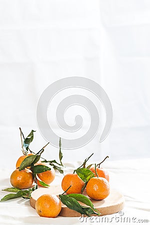 Ripe mandarins with twigs on a round board. A photo with negative space.. Stock Photo