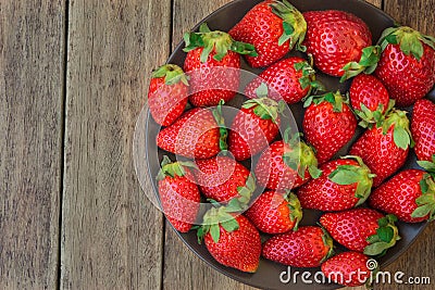 Ripe organic strawberries on dark plate on plank wood background, close up, healthy food, detox Stock Photo
