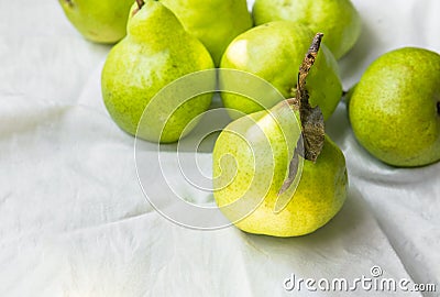 Ripe organic yellow green pears on white cotton table cloth in kitchens. Autumn fall harvest local bio produce vitamins Stock Photo
