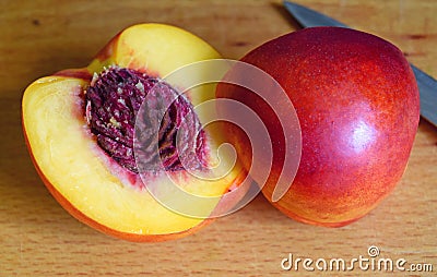 Ripe peach with a bone on a cutting board. Cut with a knife. Stock Photo