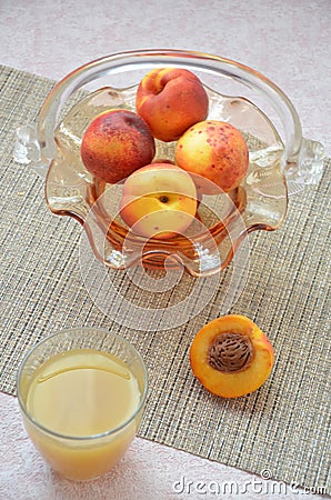 Ripe peaches and glass of juice on a table, cut peach, of a beautiful vase in the shape of a basket background. Stock Photo