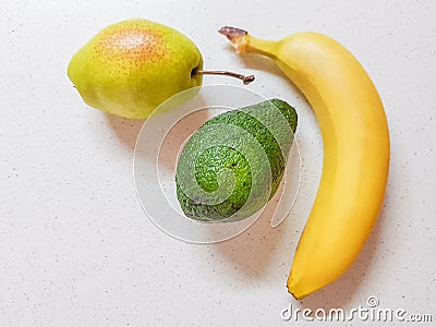Ripe pear, avocado and banana on the white marble table. Stock Photo