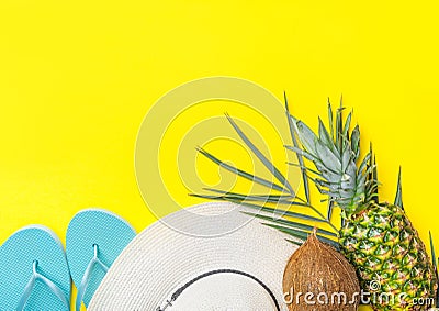 Ripe pineapple coconut on green palm leaf white straw hat blue slippers on bright yellow solid background. Summer vacation fun Stock Photo