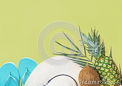 Ripe pineapple coconut on green palm leaf white straw hat blue slippers on pastel chartreuse background. Summer vacation fun Stock Photo
