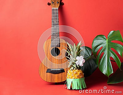 Ripe pineapple in green skirt, guitar monstera leaves coral background. The concept of relaxation and a Hawaiian party. Stock Photo