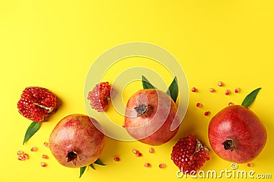 Ripe pomegranate, leaves and seeds on yellow background Stock Photo