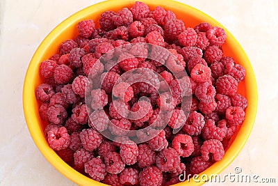 ripe raspberries in a yellow container on the table Stock Photo