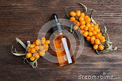 Ripe sea buckthorn and bottle of essential oil on wooden table, flat lay Stock Photo