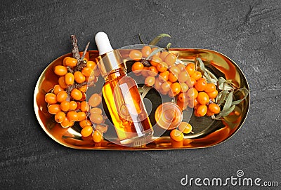 Ripe sea buckthorn and bottles of essential oil on black table, top view Stock Photo