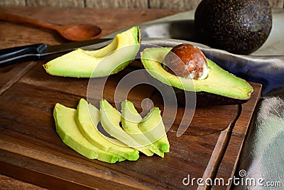 Ripe slice avocado on wooden cutting board Stock Photo