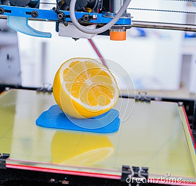 Ripe slice of lemon citrus fruit. 3d printer of the device during the processe. Stock Photo