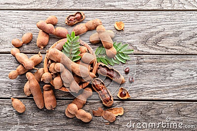Ripe tamarind fruit, leaves and some tamarind seeds on wooden table Stock Photo
