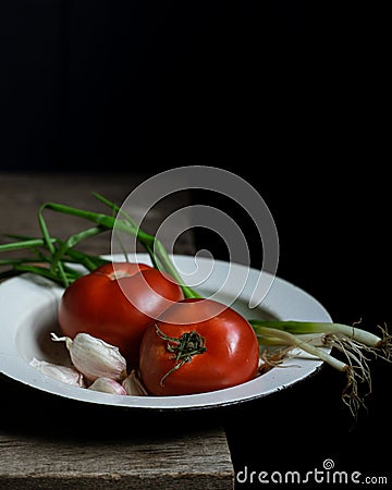 Ripe tomatoes and scallions on old wooden table Stock Photo