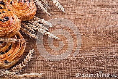 Ripe wheat ears sweet raisin buns on oaken wooden Stock Photo