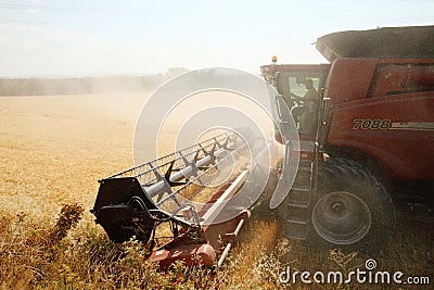 A ripe wheat field being harvested by a combine harvester. Editorial Stock Photo