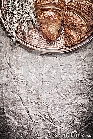 Ripe wheat rye ears sweet buns copper tray on wrapping paper Stock Photo