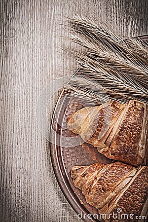 Ripe wheat rye ears sweet croissants brass tray on wooden board Stock Photo