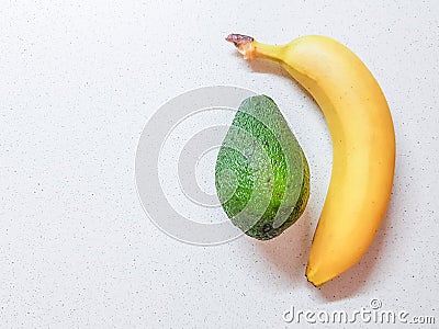 Ripe yellow banana and avocado on the white marble table Stock Photo