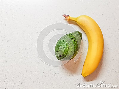 Ripe yellow banana and avocado on the white marble table Stock Photo