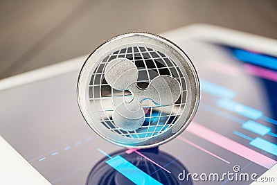 Close-up photo of ripple cryptocurrency physical coin on the tablet computer showing stock market charts. trading ripple crypto Editorial Stock Photo