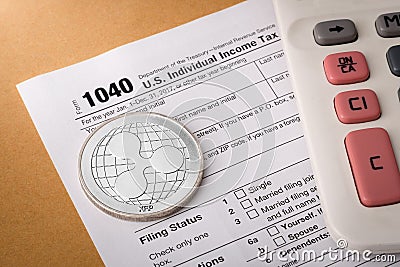 Ripple physical silver coin symbol on 1040 tax form with calculator Editorial Stock Photo