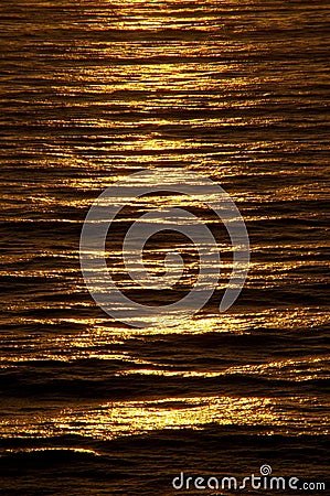 Rippled ocean surface glows with rich copper color at sundown Stock Photo