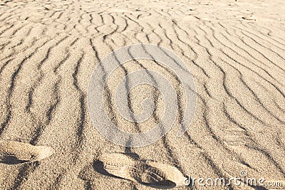 Rippled small sand on sea coast. Dunes on beach formed by wind and water. Footprints from shoes on sand Stock Photo