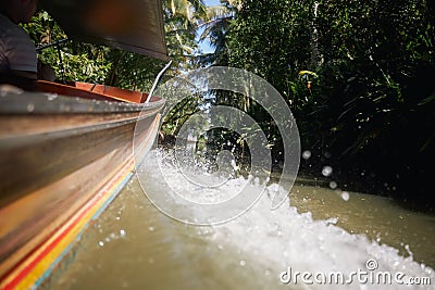 Rippled water and splashing drops behind traditional wooden long tail boat Stock Photo