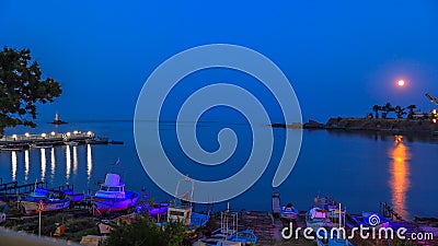 Rise of the moon over the bay of the town Ahtopol with a harbor for fishing boats, pier and lighthouse. Bulgaria. Editorial Stock Photo