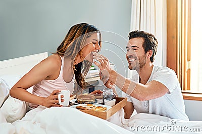 Rise and shine then wine and dine. a happy young couple enjoying breakfast in bed together at home. Stock Photo