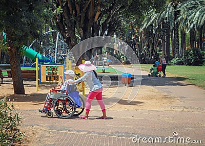 A morning stroll in the city park with invalid tender Editorial Stock Photo