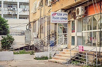 The rent apartment building with tailoring repairs sign in Russian and Hebrew Editorial Stock Photo