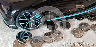Close-up of Black Bugatti Chiron metal toy with blue wheels standing on group of one Israeli shekel coins Editorial Stock Photo