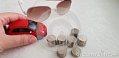 A girl holding small red fiat 500 abarth toy on white table near sunglasses and pile of Israeli one shekel coins Editorial Stock Photo