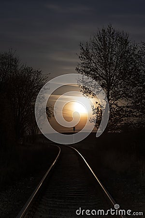 Rising full moon over a single railway-line Stock Photo