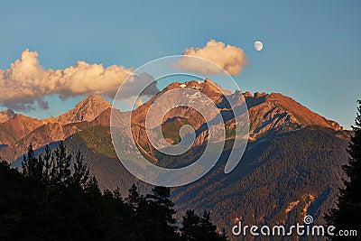 Rising moon and setting Sun over Piz Mitgel massif Stock Photo