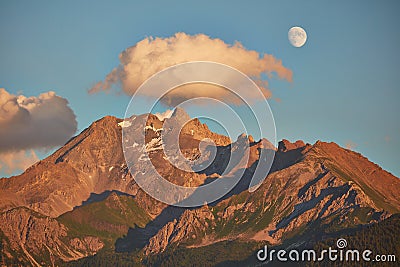 Rising moon and setting Sun over Piz Mitgel massif Stock Photo