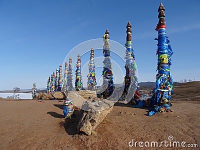 Ritual Buryat pillars on the background of sand snow and blue sky Stock Photo