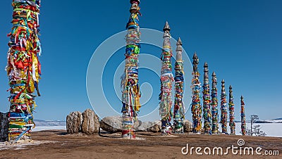 Ritual wooden pillars, tied with bright multi-colored ribbons Stock Photo